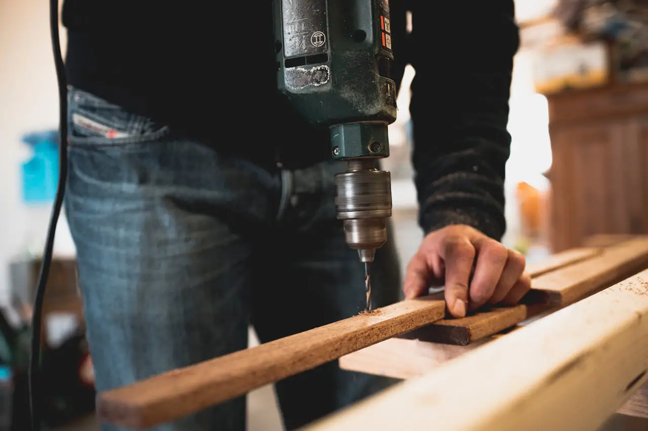 Handwerker bohrt Löcher in Holzlatten