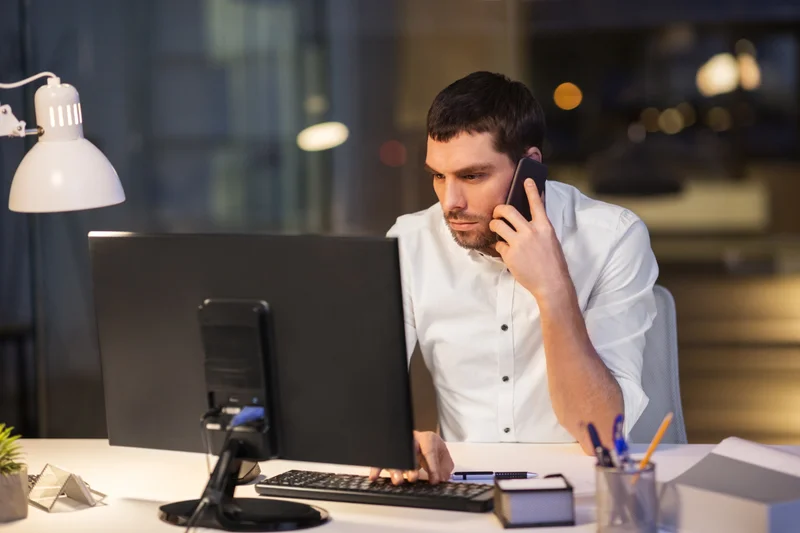 Handwerker telefoniert abends am Schreibtisch im Büro – Anfragen erreichen Dich außerhalb der Arbeitszeit