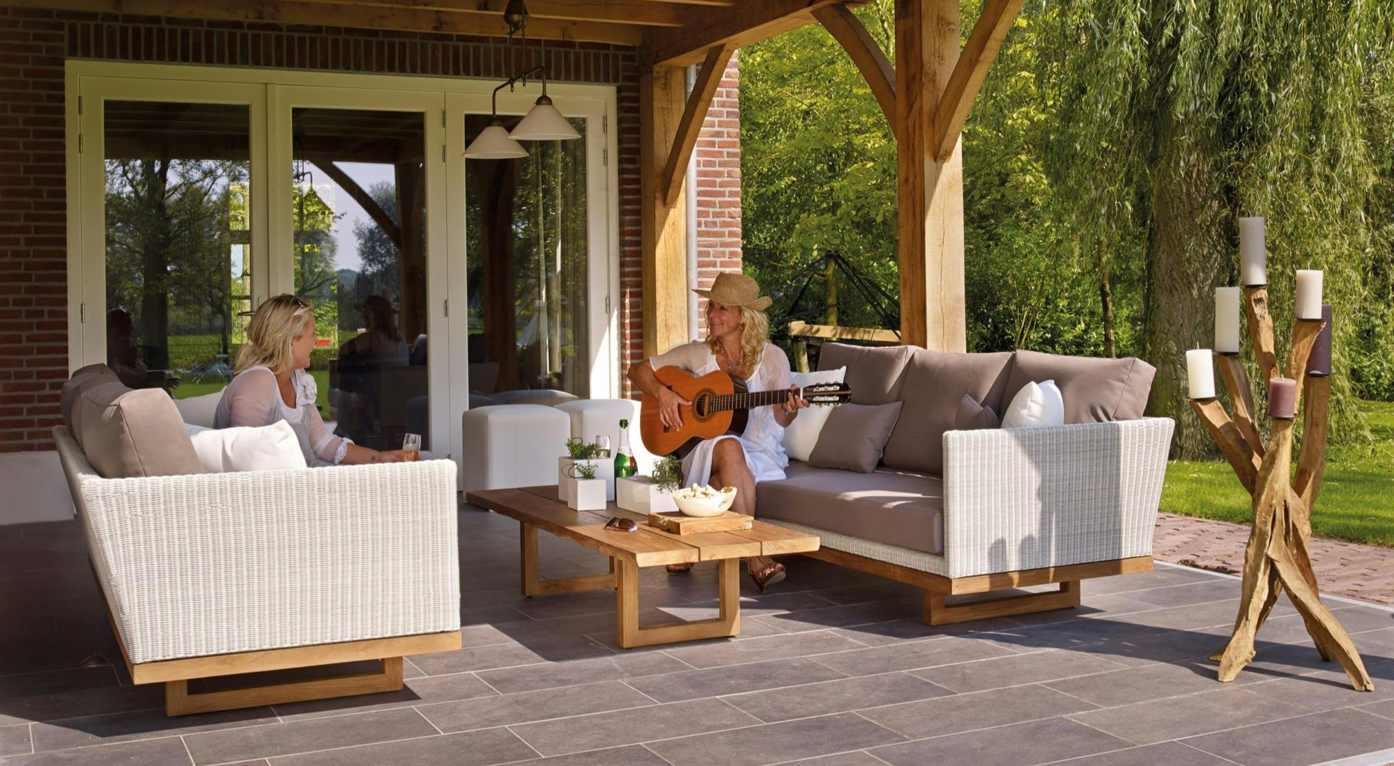 Zwei Damen sitzen auf einer Terrasse und unterhalten sich, die eine hat eine Gitarre bei sich