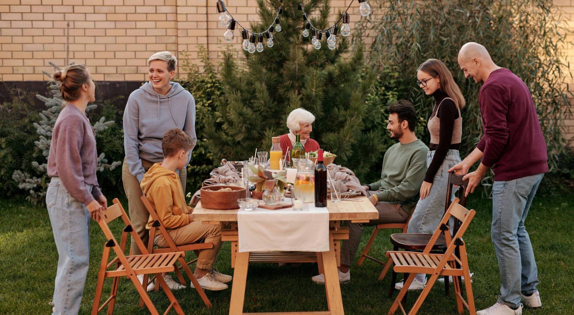 eine Familie sitzt und steht im Garten an einem Tisch und speist