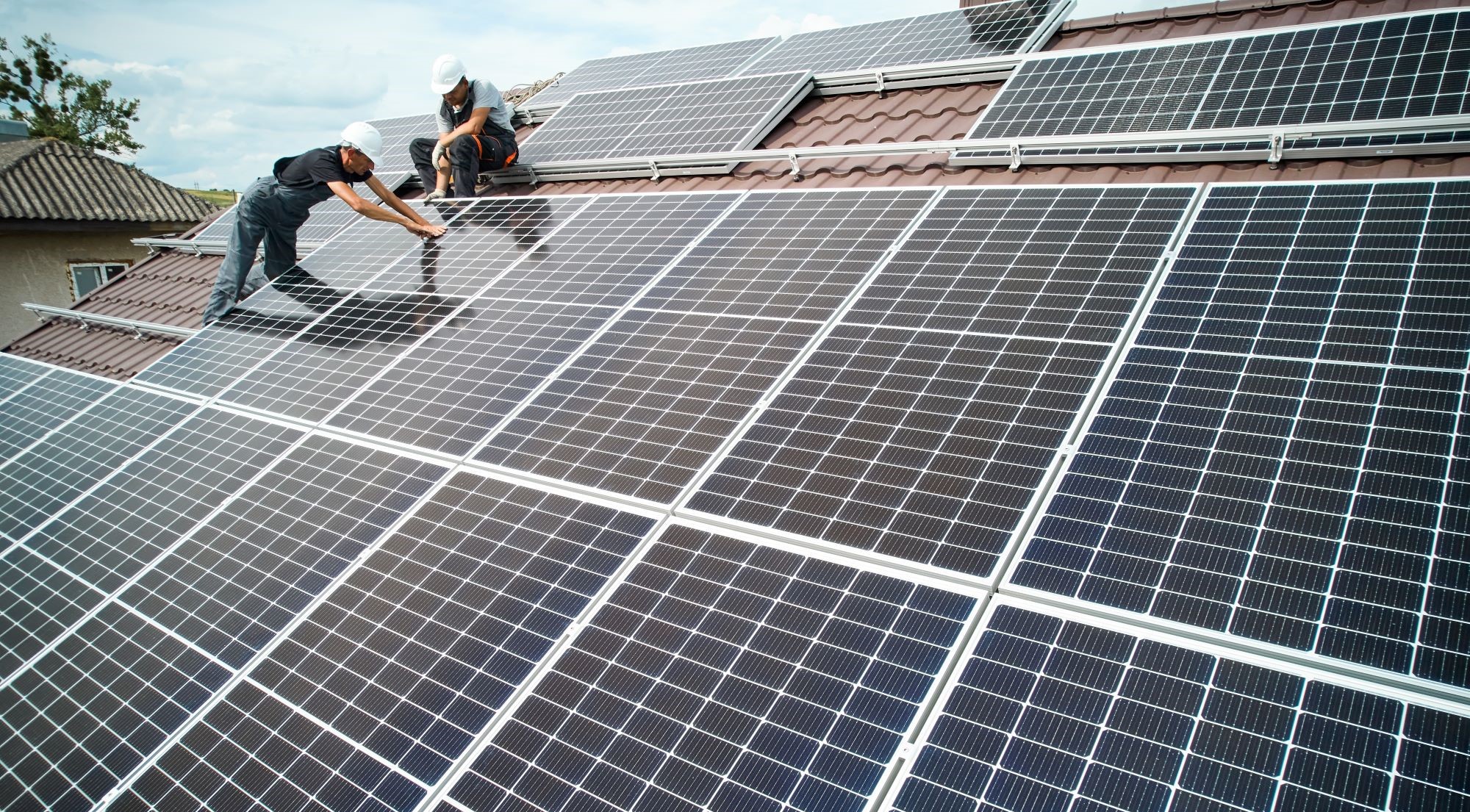 zwei Männer bauen eine PV-Anlage auf einem Dach auf