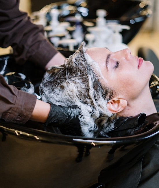 Frau bekommt die Haare beim Friseur gewaschen