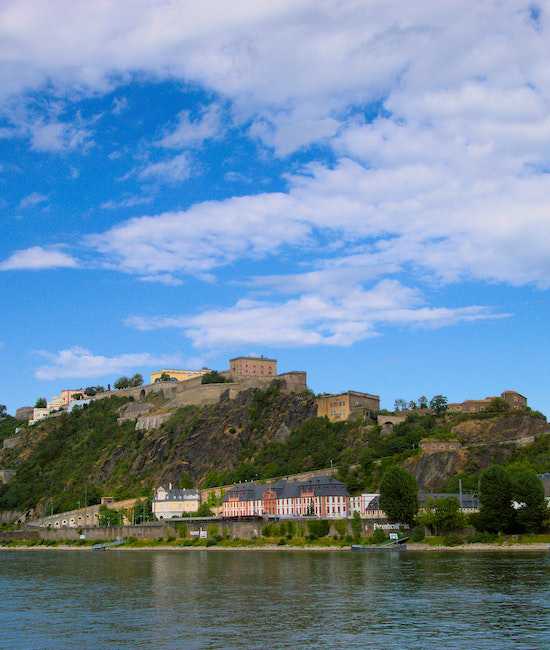 Bild von der Stadt Koblenz. Man sieht einen Fluss und eine Burg im Hintergrund