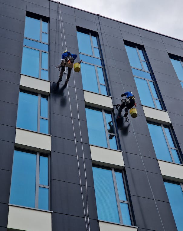 Zwei Reiniger putzen die Fenster von außen